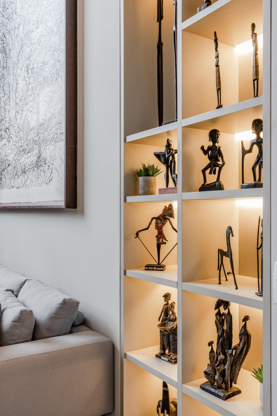 Nicho iluminado com esculturas decorativas e marcenaria em laca branca.