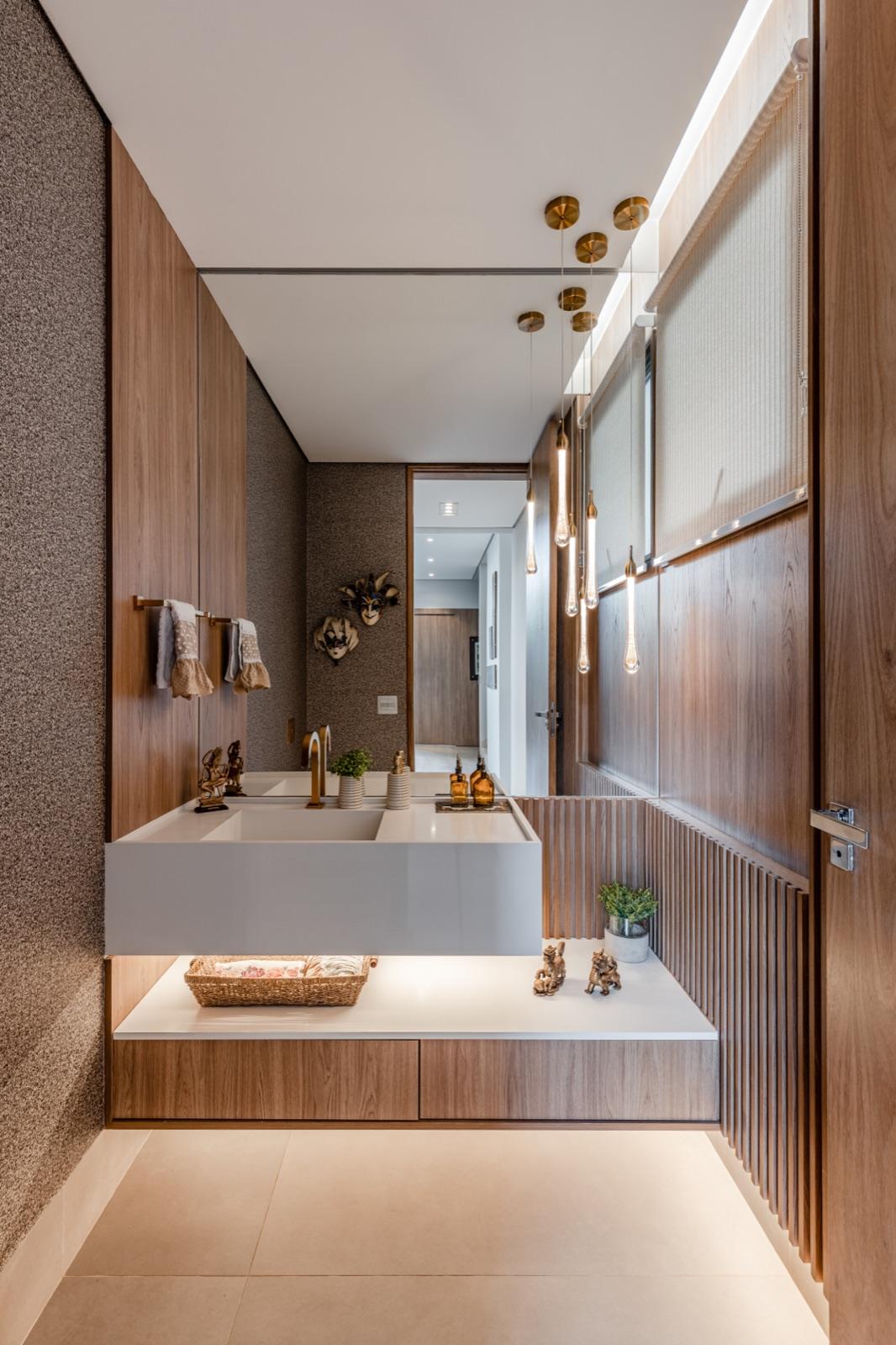 Lavabo com revestimento em madeira nobre e iluminação cênica.